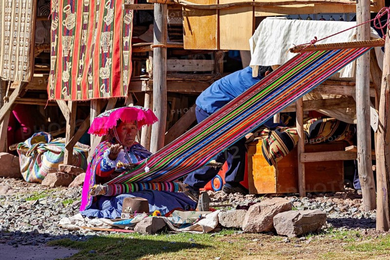 Woman weaving traditionally in Peru surrounded by colorful fabrics and craftsmanship, Elderly traditionally dressed lady from Peru weaving a cloth