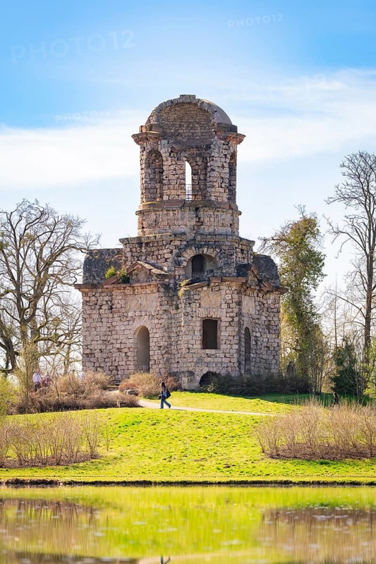 Historic tower surrounded by green nature under a blue sky, Schwetzingen Palace Gardens, Germany