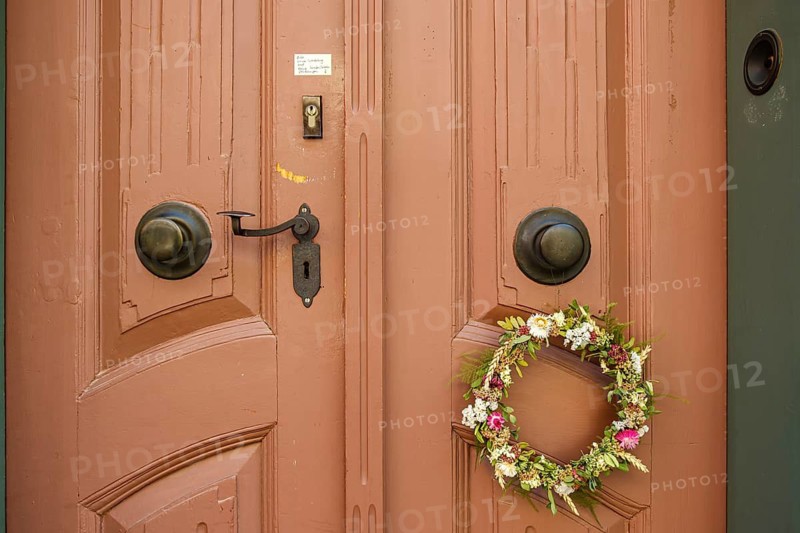 Detail of an antiquated front door with floral wreath and no advertising sign in a building on the Krämerbrücke in the historic city centre of Erfurt, Thuringia, Germany