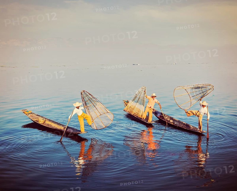 Myanmar travel attraction, Traditional Burmese fishermen balancing with their fishing net on boats at Inle lake in Myanmar famous for their distinctive one legged rowing style. Vintage filtered retro effect hipster style image