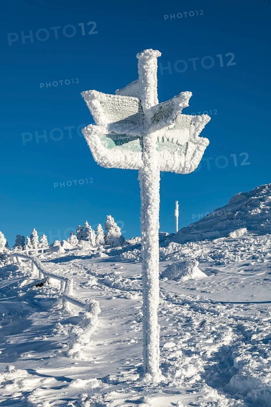 Signpost covered by snow and ice on the hiking trail on the Brocken Summit, Harz National Park, Saxony-Anhalt, Germany