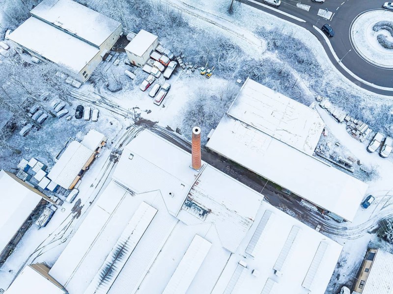 Industrial complex with high chimney, covered with snow, taken from the air, Nagold, Black Forest, Germany