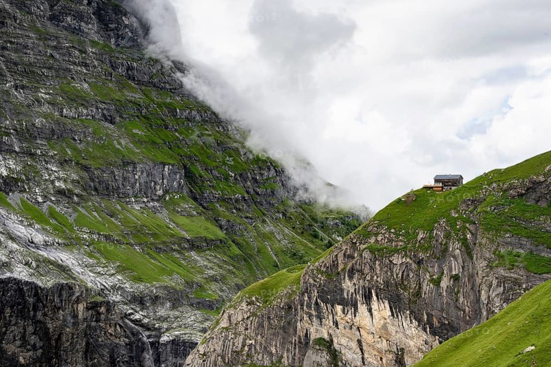 Dramatic mountain landscape covered in clouds with Berghaus Bäregg mountain hut, Bernese Alps, Bernese Oberland, Switzerland