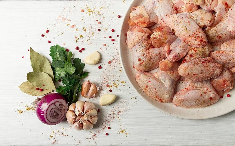 Fresh, raw chicken wings, with spices, on a white wooden table