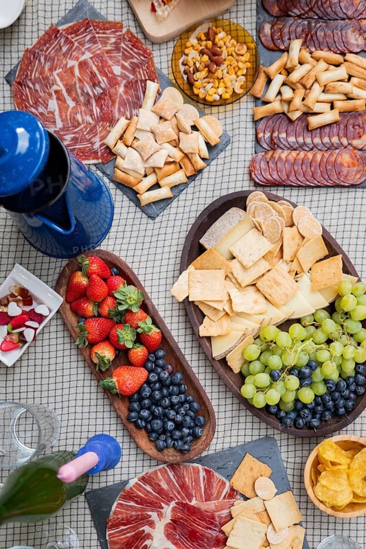 An inviting charcuterie board features assorted cheeses, cured meats, crackers, fresh strawberries, blueberries, and grapes, ideal for a cozy gathering or celebration