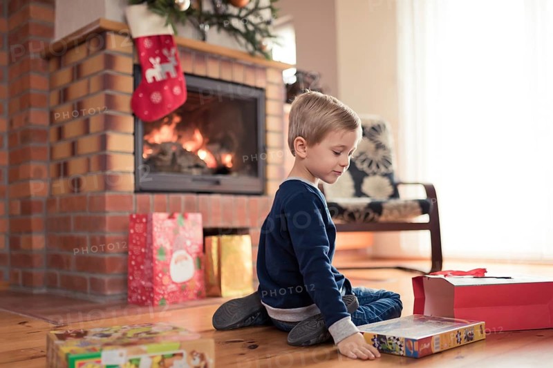 5 years old boy in front of the fireplace is happy with Christmas gifts in Tymowa, Poland