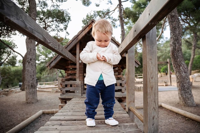 A young girl enjoys the peaceful surroundings of a forest park in the afternoon. She is immersed in nature, exploring her environment, with tall trees encircling her