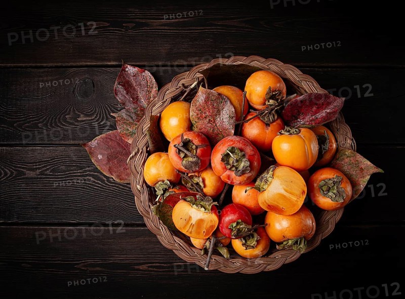 Fresh persimmon in a basket, with leaves, top view, no people