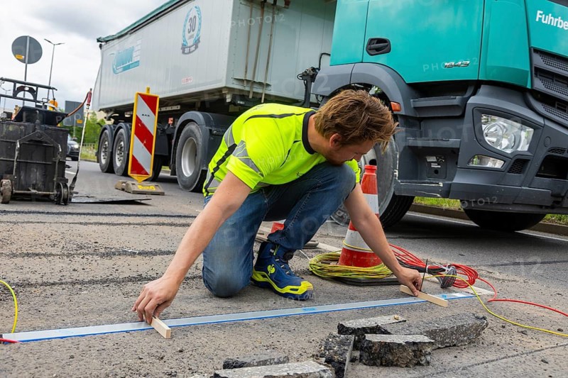 As part of the Smart City model project, several measurement points are being set up in Dresden's main transport network. Axle load sensors, contact loops and temperature sensors are placed on the road. They record data, such as the weight of the passing vehicles. The technology for such a measuring point is currently being installed on the B170/ Bergstraße in the direction of the city between Kohlenstraße/Südhöhe. The data can then be used to create model calculations for road conditions and the necessary maintenance intervals. An employee from Kistler uses a measuring bar, Dresden, Saxony, Germany