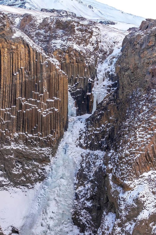 Hengifoss waterfall frozen in the cold Icelandic winter, detail of the volcanic cliffs