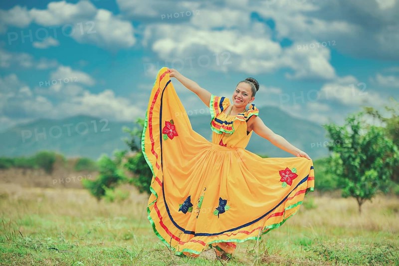 Hispanic girl in national folk costume in a field smiling at camera
