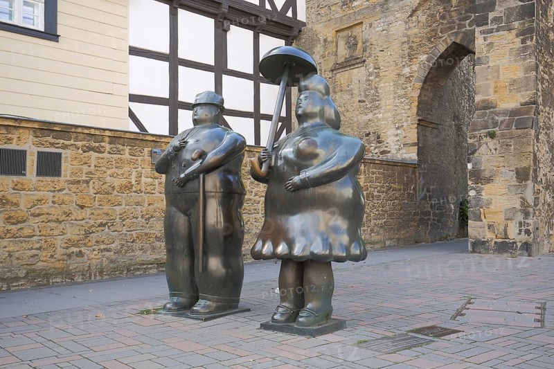 Sculpture man with stick and woman with umbrella by Fernando Botero, modern art, two chubby bronze sculptures, fat couple, cheesy, ugly, ugly, walking stick, umbrella, life-size, rose gate, Goslar, Harz, Lower Saxony, Germany