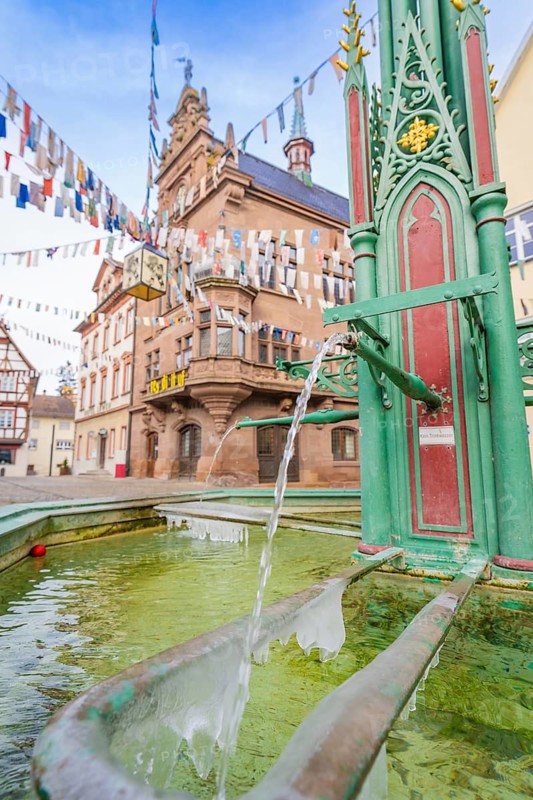 Historic town square with green fountain and colourful pennants in front of an old building, Meßkirch, Sigmaringen district, Germany