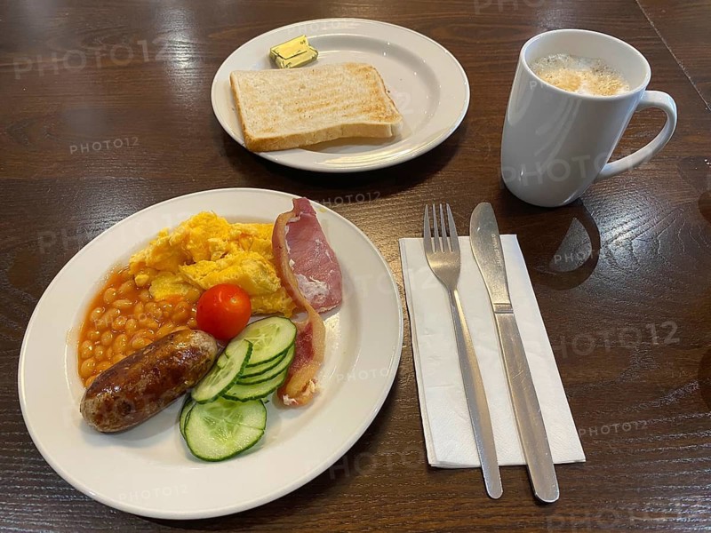 English breakfast on plate with scrambled eggs, baked beans, bacon, sausage, pickles, tomatoes, toast, butter, coffee, silverware, greasy, food, London, Great Britain, Great Britain