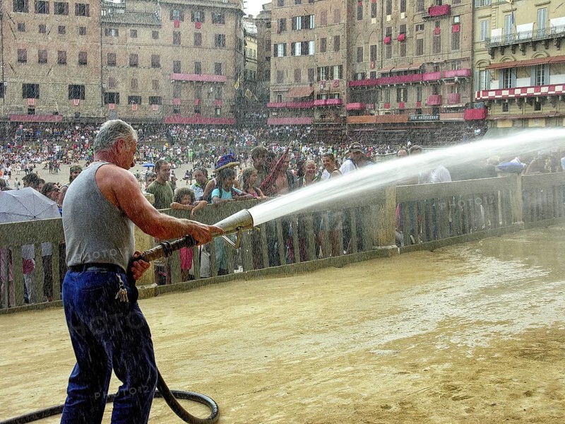 Il Palio di Siena, historic horse race, worker waters the sand and tuff racecourse with water from a fire hose, Piazza del Campo, historic centre, Siena, Tuscany, Italy