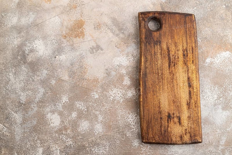 Empty rectangular wooden cutting board on brown concrete background. Top view, copy space, flat lay