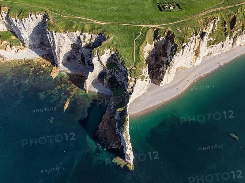 Aerial view, top-down view of the Falaise d'Amont rock formation and viewpoint, Porte d'Amont in the evening sun, a landmark and natural beauty on the chalk coast with the distinctive rock gate, Étretat, Alabaster Coast, La Côte d'Albâtre, Seine-Maritime, Normandy, France