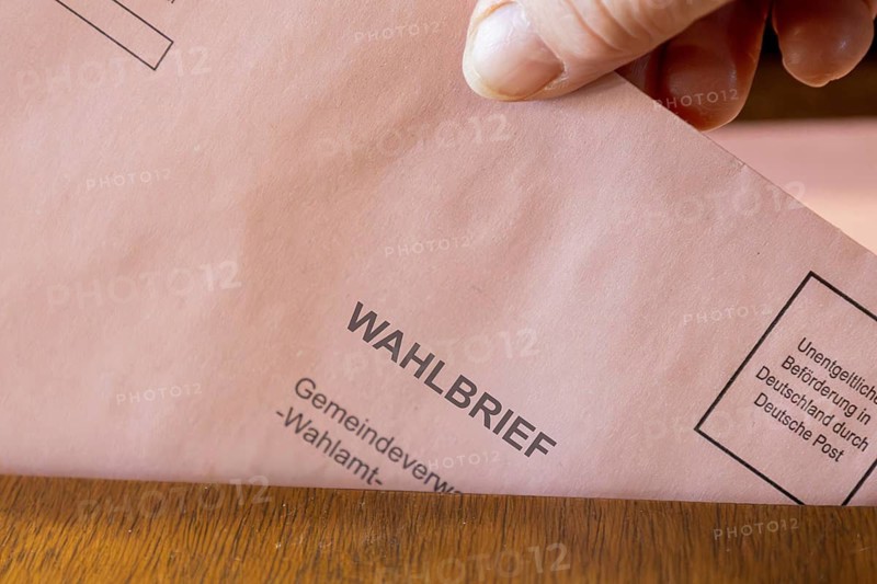 Absentee voting symbol: A ballot letter is thrown into the ballot box of a municipal administration