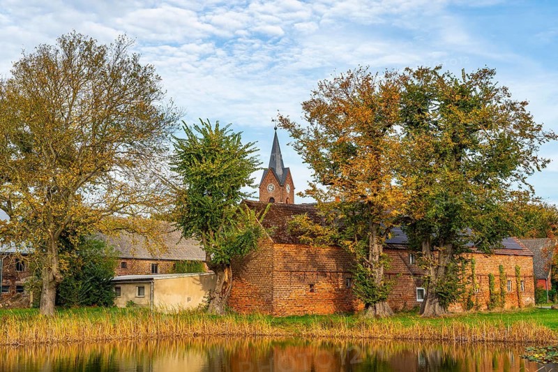 Village pond, farm and church in Oehna in autumn, Niedergörsdorf, Fläming, Brandenburg, Germany