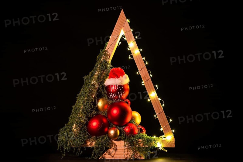 Modern DIY wooden Christmas tree with LED lights, moss, red balls and ornaments on a neutral background