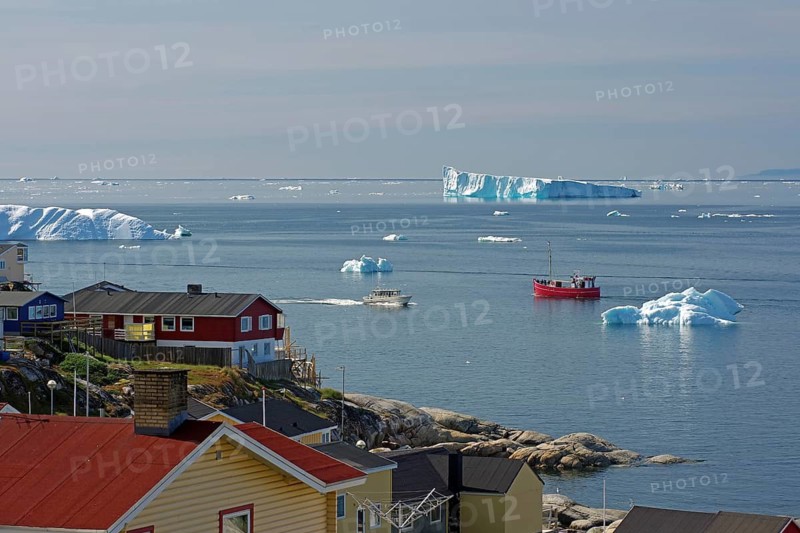 A quiet coastal town with boats in the sea and icebergs on the horizon, Arctic, Disco Bay, Ilulissat Greenland, Denmark