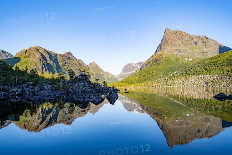 Picturesque mountain landscape in the Innerdalen high valley, Innerdalstårnet peak reflected in Lake Innerdalsvatna, in the evening light at sunset, Trollheimen Mountain Area, Sunndal, Møre og Romsdal, Norway