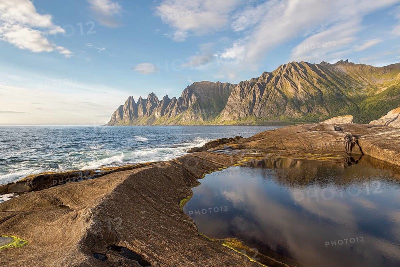 Tidal pool on Tungeneset cliffs with views of the sea and Okshornan Mountains, Senja, Norway