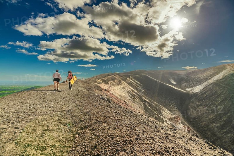 View of two people walking at the top of a volcano. Scene of tourists walking at the summit of the Cerro Negro volcano