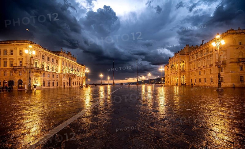 Illuminated square Piazza Unità d'Italia, Palazzo del Lloyd Triestino and Palazzo della Luogotenenza Austriaca or Palazzo Governo, with reflection, dramatic clouds, blue hour, old town, Trieste, Friuli-Venezia Giulia region, Italy