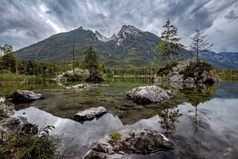 Mountain landscape with lake surrounded by trees and rocks, dramatic clouds over the Alps, The Hintersee near Berchtesgaden in Bavaria
