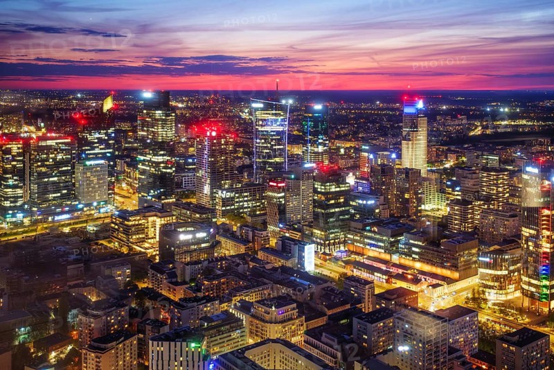 High viewpoint over the Warsaw skyline in Poland with skyscrapers, city lights, city grid, blue hour twilight and evening glow