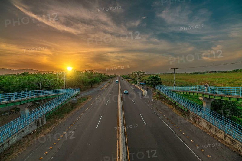 Aerial view of a road at sunset with vehicular traffic. Sunset landscape featuring urban traffic surrounded by nature