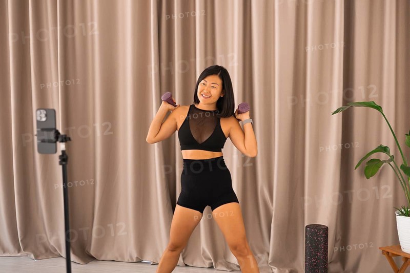 Woman smiling during a workout, lifting dumbbells in an indoor setting