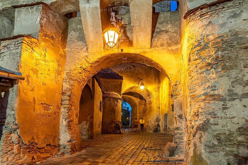 Portal to the citadel under the hour tower at dusk, Sighisoara or Sighi?oara, Transylvania, Romania