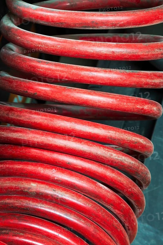Close-up of large red coiled heavy duty hose of air compressor machine in home garage workshop, Quebec, Canada