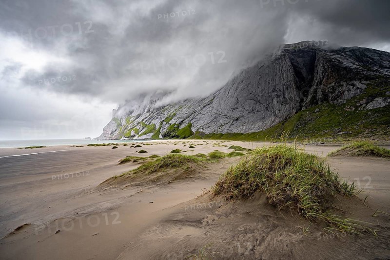 Sand dunes on sandy beaches Bunesstranden between rocky mountain peaks and dramatic clouds, Lofoten, Norway