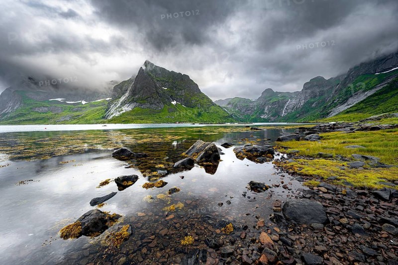 Shore with reflection, fjord landscape with mountains and dramatic clouds, Vindstad, Reinefjord, Lofoten, Norway