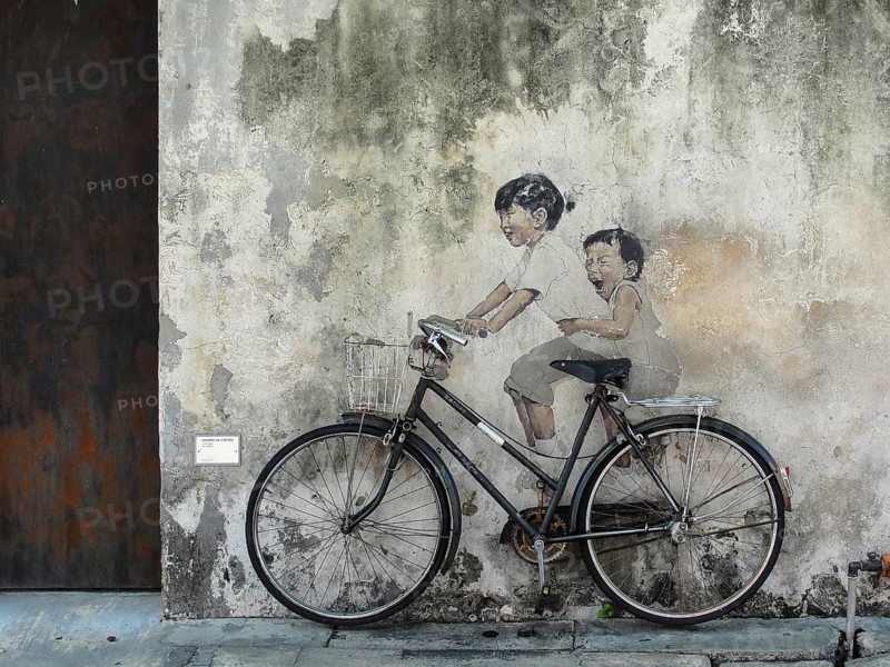 Little Children on a Bicycle street art on wall by Lithuanian artist Ernest Zacharevic in George Town, Penang, Malaysia, travel photo, A mural of two children on a bicycle painted on a weathered wall, creating a nostalgic, playful urban scene, George Town, Penang, Malaysia