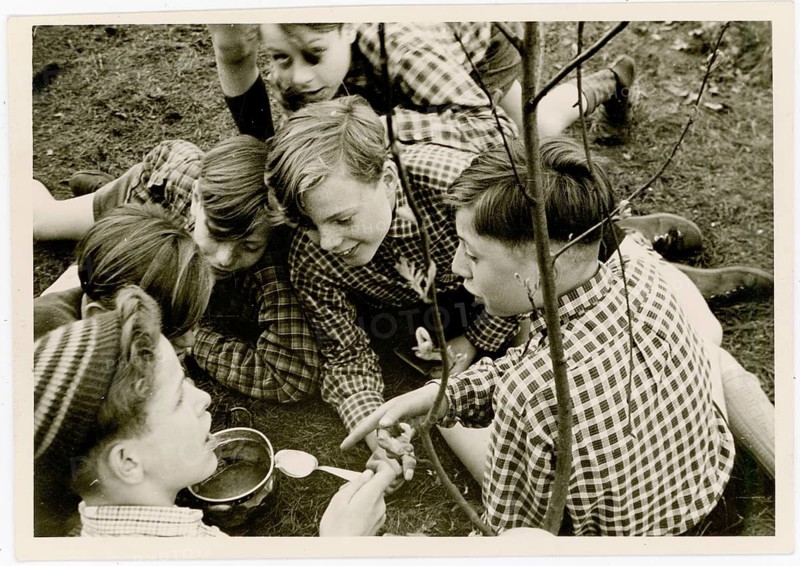 Outdoor picnic, rascal, excursion, hiking trip, group of boys sitting together outdoors, engaged in conversation, around 1932