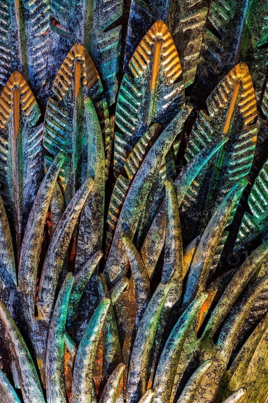 Close-up of golden, greenish and turquoise painted carved metal feather details on ornamental waterbird sculpture, Quebec, Canada