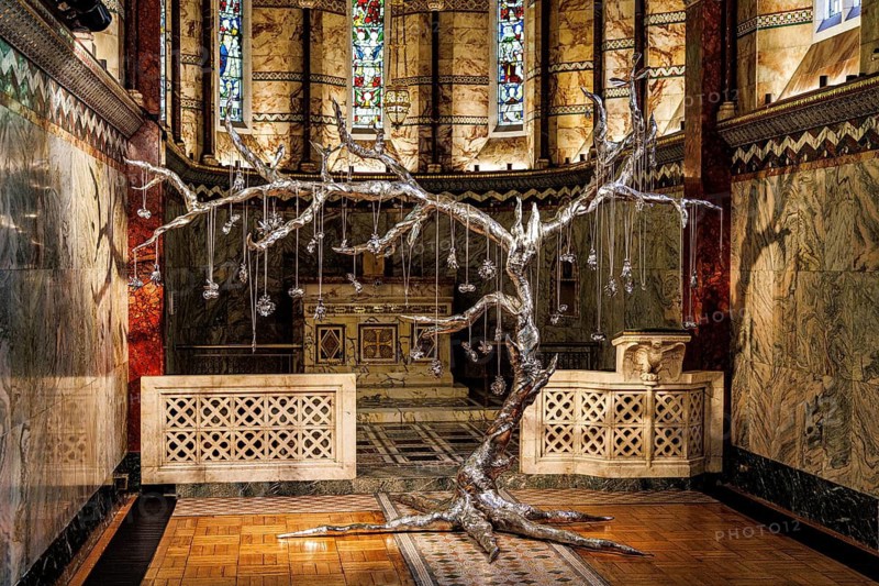 Silver tree sculpture stands beneath stained glass in the marble chancel of Fitzrovia Chapel, London, England, United Kingdom