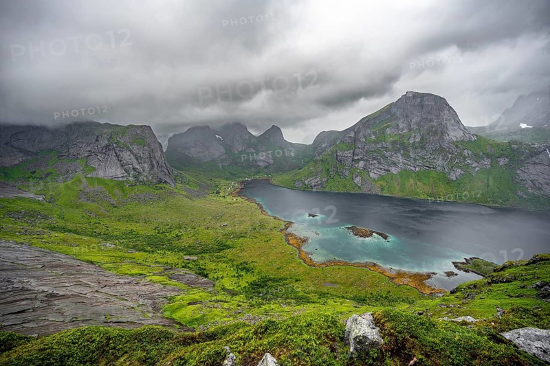 View over Kjerkfjorden fjord, mountain peaks and dramatic clouds, climb to Helvetestinden summit, Lofoten, Norway