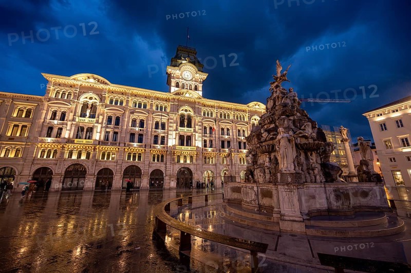 Illuminated square Piazza Unità d'Italia, Town Hall, Palazzo Communale and Fontana dei Quattro Continenti fountain, with reflection, dramatic clouds, blue hour, old town, Trieste, Friuli-Venezia Giulia region, Italy
