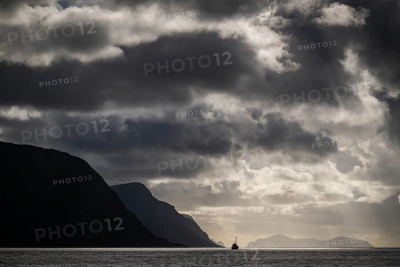 Dramatic lighting and dark clouds over the sea, island, ship, near Ålesund or Alesund, Møre og Romsdal Fylke, Norway