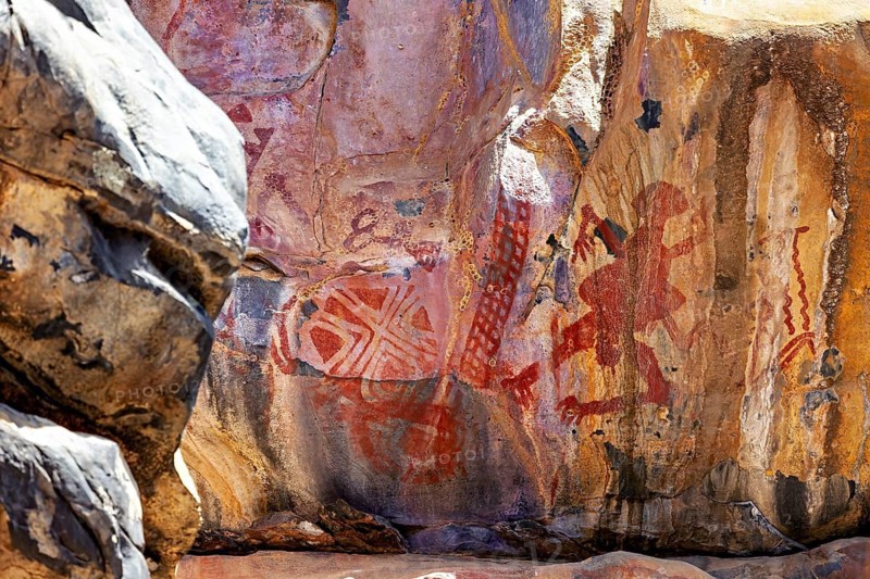 Red symbols and human figures on rough rock surface, prehistoric rock carvings in the thorny savanna of Caatinga in Brazil