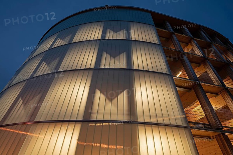 03.05.2026: Illuminated modern timber parking garage (Parkhaus am Bahnhof) with a curved wooden facade at dusk. Wendlingen am Neckar, Baden-Württemberg, Germany
