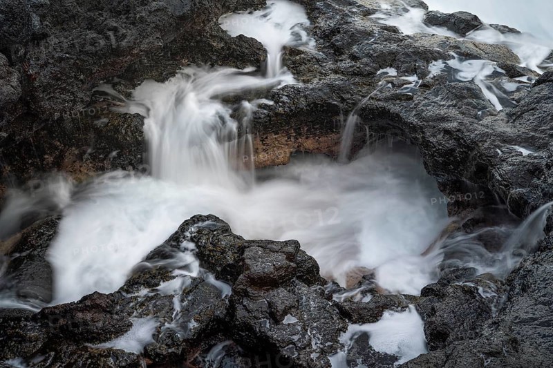 Seawater flows over lava rocks into a small pool. long exposure. Coast near Charco Azul, La Palma, Canary Islands, Spain