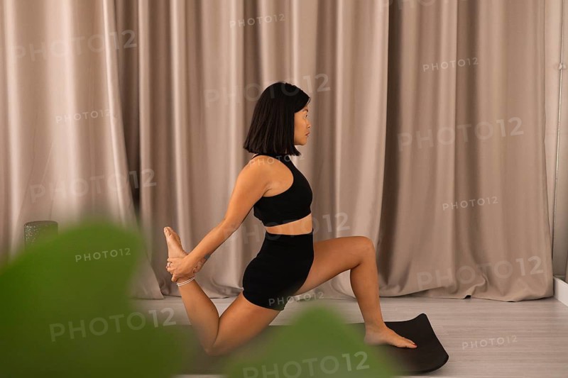 Yoga practice scene with woman in stretch pose on mat, surrounded by calm indoor aura