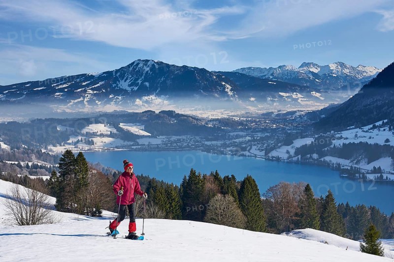 Sportive senior woman hiking with snow shoes in the snowy Allgaeu Alps above Lake Alosee, Immenstadt, Bavria, Germany