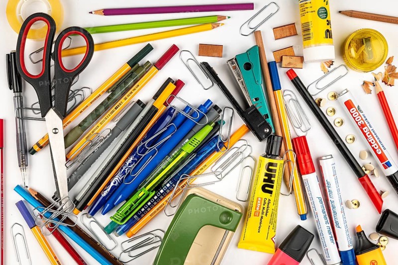 A jumble of stationery and office supplies on a white surface